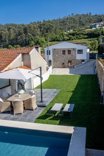 a patio with chairs and an umbrella next to a pool at Casa Gondiga in Roriz