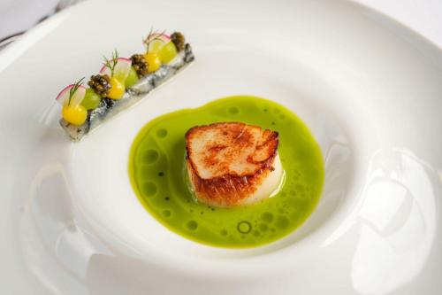 a plate with a piece of fish on a green sauce at Farlam Hall Hotel & Restaurant in Brampton