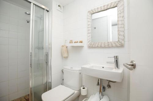ein Badezimmer mit einem WC, einem Waschbecken und einem Spiegel in der Unterkunft L'Hostalet de Cadaques in Cadaqués