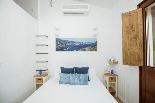 um quarto com uma cama com lençóis brancos e almofadas azuis em L'Hostalet de Cadaques em Cadaqués