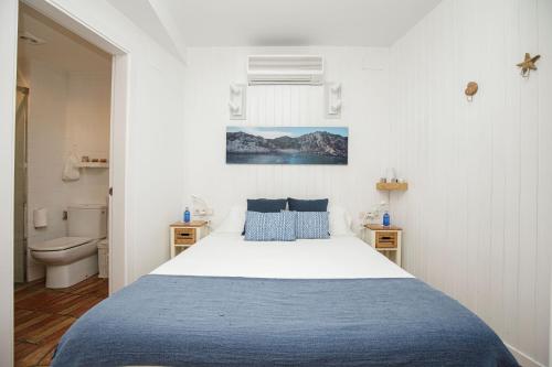 a white bedroom with a bed and a toilet at Hostalet de Cadaques by Suma Hotels in Cadaqués