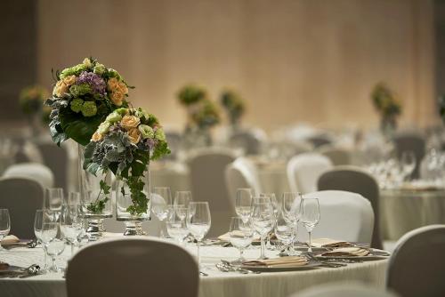 a table with glasses and a vase with flowers on it at Shangri-La Tangshan in Tangshan
