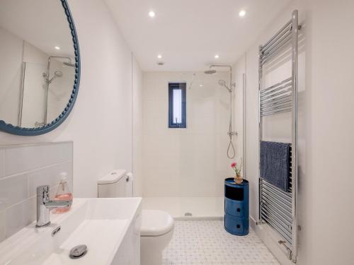 bagno bianco con servizi igienici e specchio di The Gatehouse uk46101 a Holt