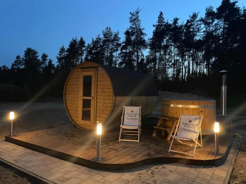 a tiny house with two chairs and a table and lights at Leśne Apartamenty in Bobolice
