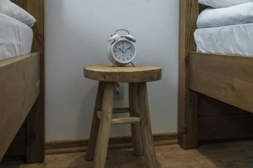 a clock sitting on a stool in a bedroom at Leśne Apartamenty in Bobolice