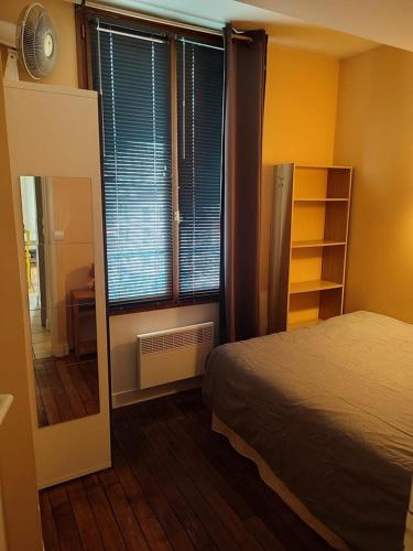 une chambre avec un lit et une grande fenêtre dans l'établissement Chez Antoine, à Boulogne-Billancourt
