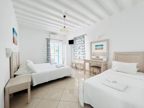 a white room with two beds and a desk at Cyclades Blue in Ornos