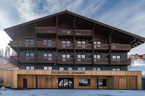 an apartment building with a wooden facade in the snow at Erzherzog Johann Alpin Style Hotel - Adults Only in Schladming