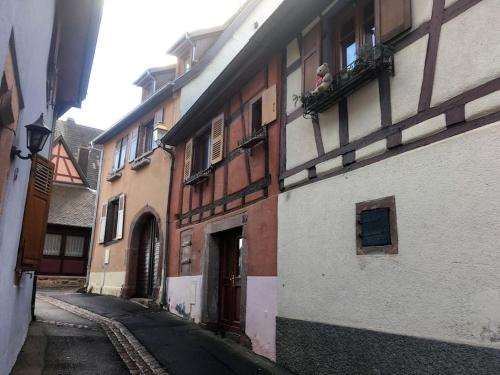 une ruelle dans un vieil immeuble avec une personne assise sur un balcon dans l'établissement Studio cosy dans maison alsacienne, à Gueberschwihr