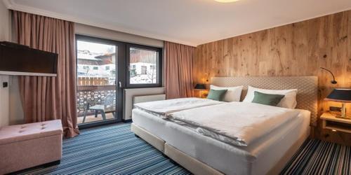 a bedroom with a large bed and a large window at Erzherzog Johann Alpin Style Hotel - Adults Only in Schladming
