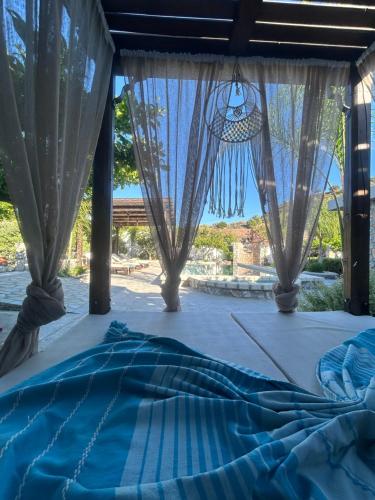a bed with a blue comforter in front of a window at Aithonas Villa in Archangelos