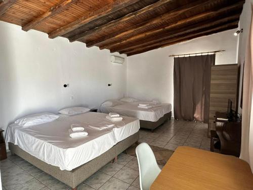 1 Schlafzimmer mit 2 Betten, einem Tisch, einem Tisch und Stühlen in der Unterkunft Villa Nikos Koukounaries in Koukounaries