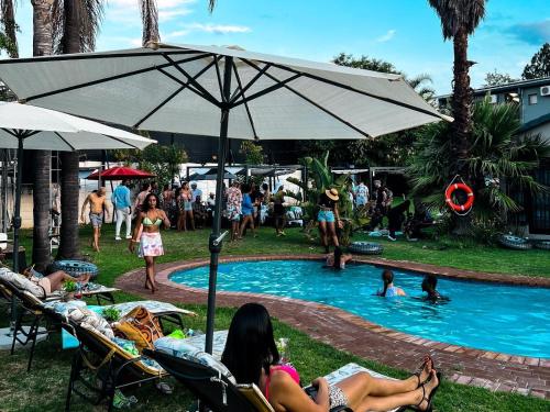 a group of people sitting around a pool with an umbrella at Monte La Vue Hotel in Sandton