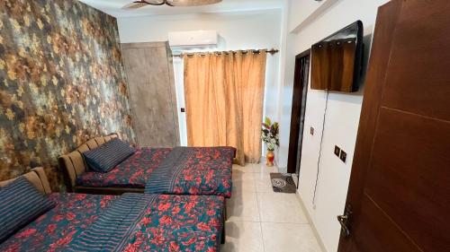 a bedroom with two beds and a flat screen tv at Residential Apartment Complex El-cilo B 414 in Islamabad