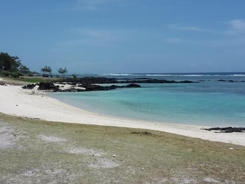 a beach with blue water and rocks in the ocean at Paradisia Holidays Mauritius in Trou dʼ Eau Douce