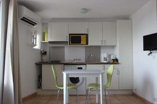 une cuisine avec des placards blancs et une table et des chaises blanches dans l'établissement Charmant studio sur le port, à Kamiesch