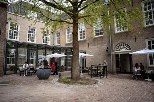 personas sentadas en mesas frente a un edificio en Stadsklooster Dordt Hotel&Hostel en Dordrecht