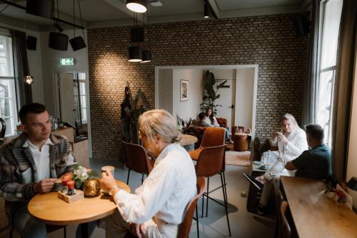un grupo de personas sentadas en mesas en un restaurante en Stadsklooster Dordt Hotel&Hostel en Dordrecht