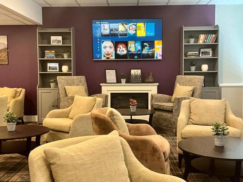 a living room with chairs and a tv on a wall at Britannia Inn Glasgow in Glasgow