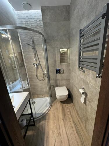uma casa de banho com um chuveiro, um WC e um lavatório. em Aparthotel Łódź 55 Piotrkowska em Lódź
