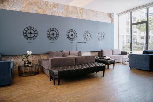 uma sala de estar com um sofá e cadeiras e relógios na parede em Impresamente Art Hotel em Sófia