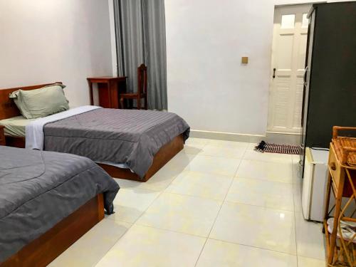 a bedroom with two beds and a tiled floor at Orchid 101 in Kampot