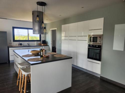 une cuisine avec des armoires blanches et un comptoir noir dans l'établissement Villa contemporaine, à Servian