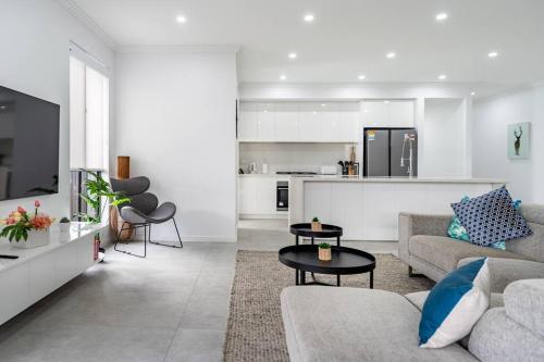 Una sala de estar con un sofá y una cocina. en Neat 4 Bedroom in Catherine Fields, en Narellan
