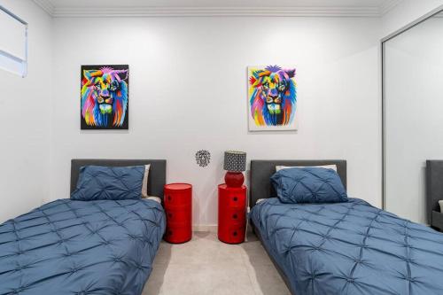 2 camas en una habitación con pinturas en la pared en Neat 4 Bedroom in Catherine Fields, en Narellan