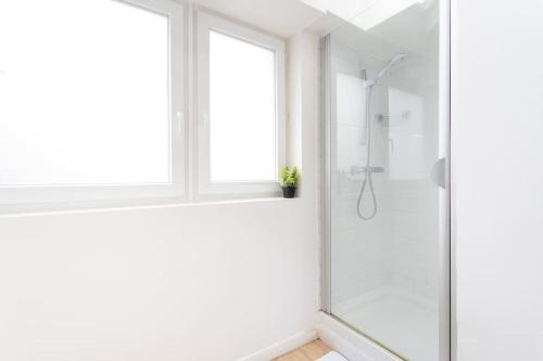La salle de bains blanche est pourvue d'une douche et d'une fenêtre. dans l'établissement Appartement agréable et spacieux 2 chambres 2 SDB - Lille, à Lille