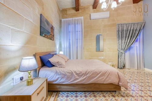 a bedroom with a bed and a table with a lamp at LUX Villa with Private Pool, BBQ & Rooftop Oasis by 360 Estates in Il-Wileġ