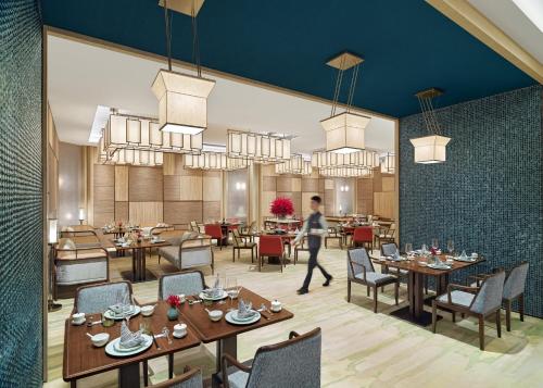 a person walking through a restaurant with tables and chairs at Mandarin Oriental, Shenzhen in Shenzhen
