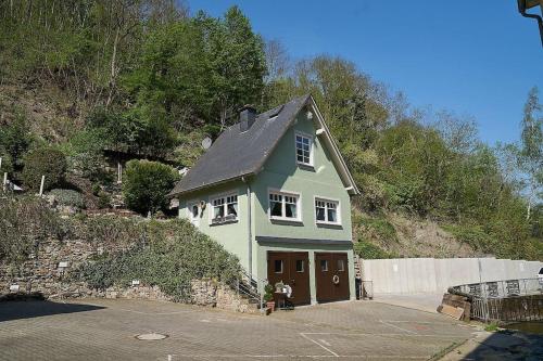 a green house with a garage in a parking lot at Ferienhaus mit Whirlpool und Sauna in Bernkastel-Kues