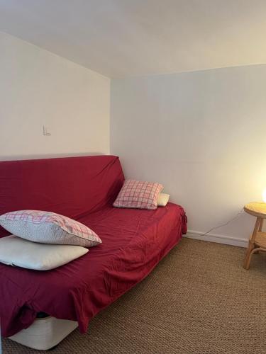 a bedroom with a red bed with pillows on it at La parenthèse cabourgeaise in Cabourg