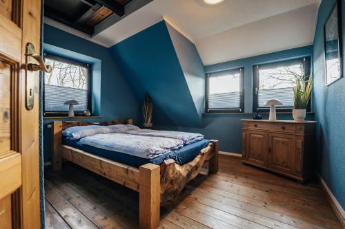 a bedroom with blue walls and a bed with a wooden floor at Gemütliche Ferienwohnung in Schneverdingen