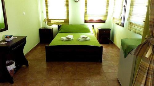 een slaapkamer met een groen bed en handdoeken bij Pension Anastasia in Amoliani