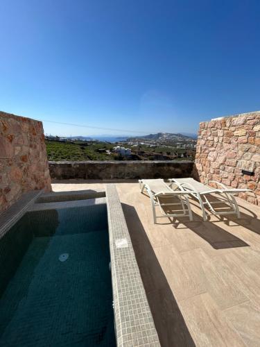 una piscina con due sedie a sdraio su un patio di Aroma Cavas a Pyrgos
