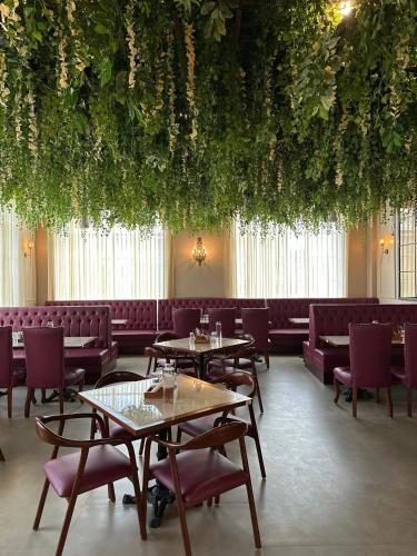 a restaurant with tables and chairs and plants hanging from the ceiling at La Nature Hotels & Resorts in Sīkar