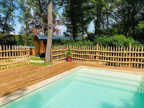 una piscina en un patio trasero con una valla de madera en Les Roulottes de l Herm Piscine Jacuzzi Perigord en Rouffignac Saint-Cernin