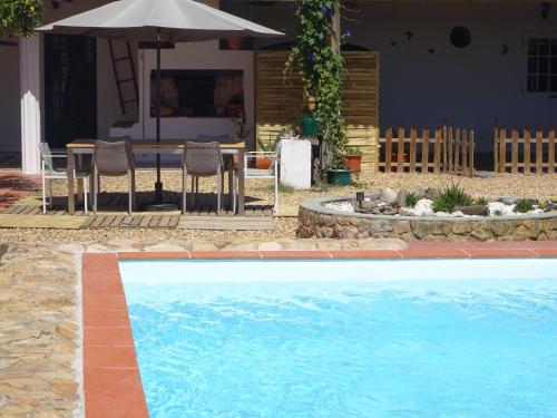 a swimming pool with a table and chairs and an umbrella at New Village in Vila Nova da Baronia