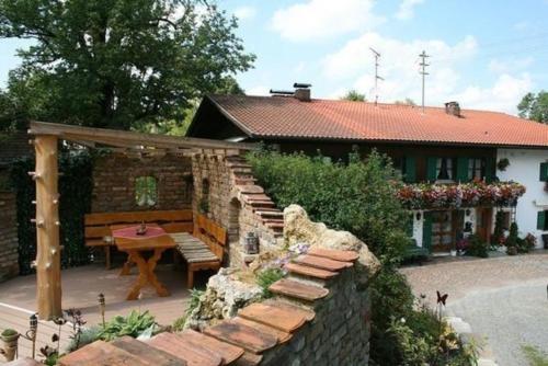 a house with a bench and a table and a stone wall at Ferienwohnung in Bad Bayersoien mit Terrasse, Grill und Garten in Bad Bayersoien