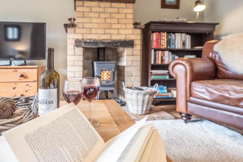 a bottle of wine and a book on a table with wine glasses at The Coach House, Reydon in Reydon