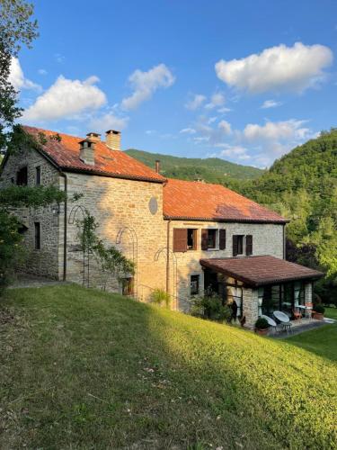 Ein altes Haus auf einem Hügel neben einem Feld in der Unterkunft Ca' Maranghi Holiday House in Palazzuolo sul Senio