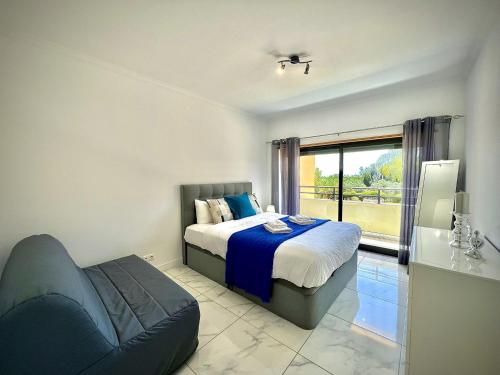 a bedroom with a bed and a couch and a window at Vilamoura Prestige 2 With Pool by Homing in Vilamoura