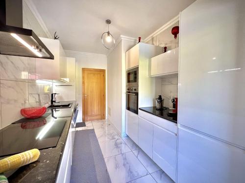 a kitchen with white cabinets and black counter tops at Vilamoura Prestige 2 With Pool by Homing in Vilamoura
