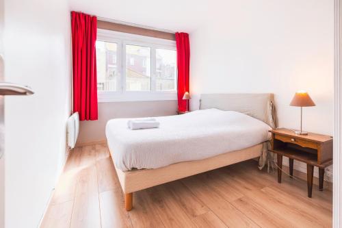 une chambre avec un lit et une fenêtre avec des rideaux rouges dans l'établissement Spacieux appart pour 6, front de mer, centre, à Le Touquet-Paris-Plage