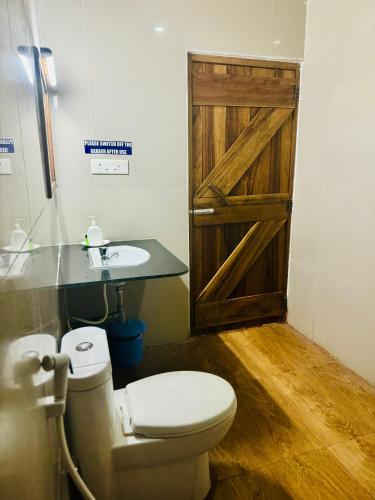 a bathroom with a wooden door and a toilet and a sink at PRISTINE BEACH RESORT in Diglipur