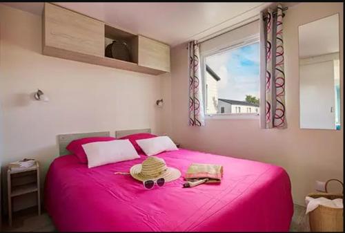 a bedroom with a pink bed and a window at Mobil home XL 6 personnes Camping 4 étoiles La Pommeraie de l'Océan in Trégunc