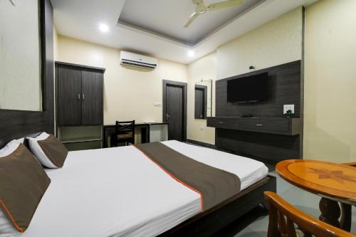 1 dormitorio con cama, mesa y TV en Collection O Hotel Silver Inn, en Bhopal