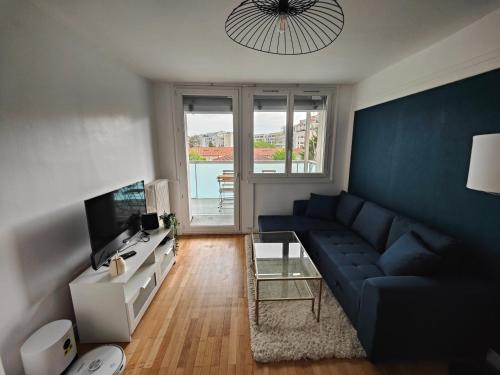 un salon avec un canapé bleu et une télévision dans l'établissement Appartement T4 avec terrasse et parking, à Villeurbanne